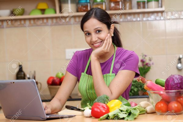 27236620-Young-Indian-woman-using-a-tablet-computer-in-her-kitchen--Stock-Photo